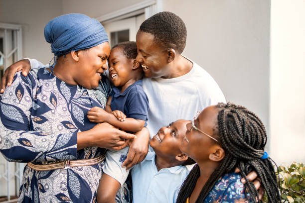 Loving African parents and their adorable young children standing together at the front porch of their home